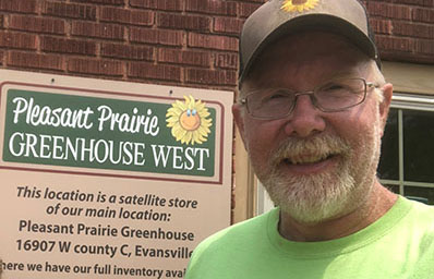man by greenhouse sign that reads, "Pleasant Prairie Greenhouse West"