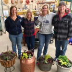women with flower pots inside greenhouse