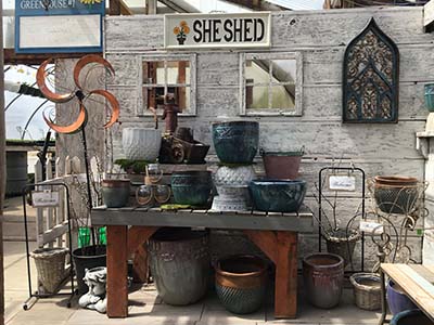 greenhouse interior with sign saying "she shed", ceramic pots, and garden decor