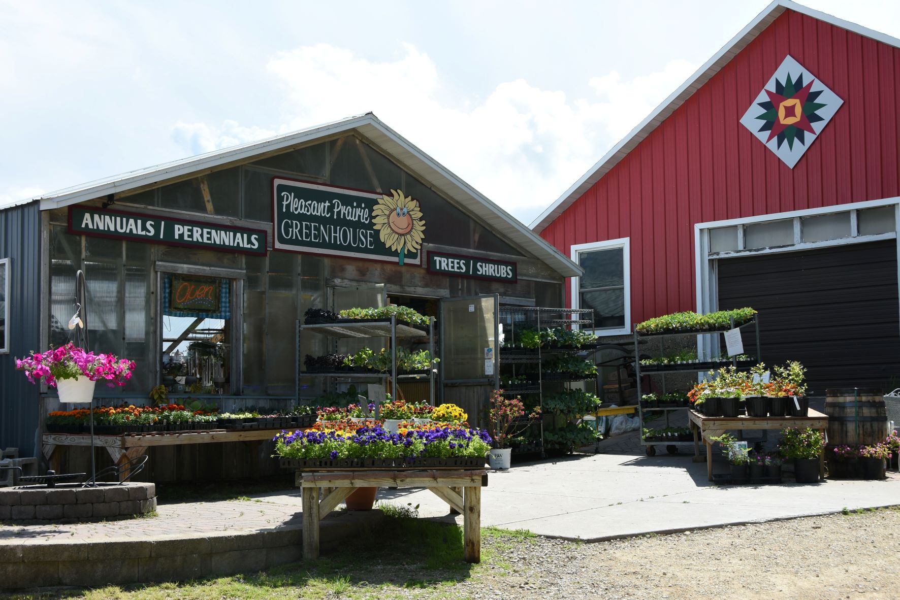exterior of greenhouse entry with sign that reads, "Pleasant Prairie Greennouse, annuals, perennials, trees, shrubs"